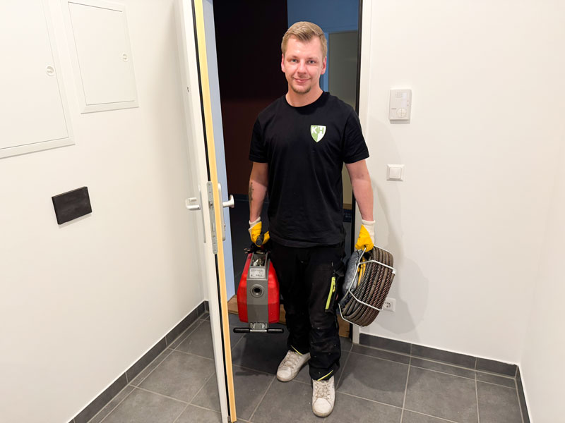 Der Kanalheld-Techniker kommt mit einem freundlichen Lächeln und seinem Werkzeug bei der Tür herein